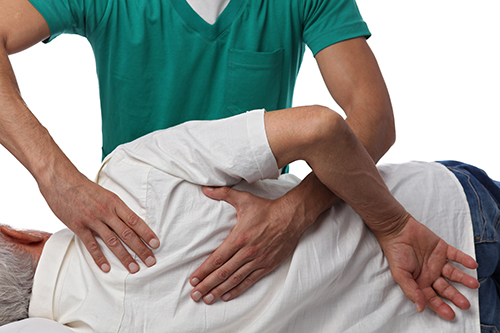 Professional physiotherapist performing manual therapy techniques on patient's back